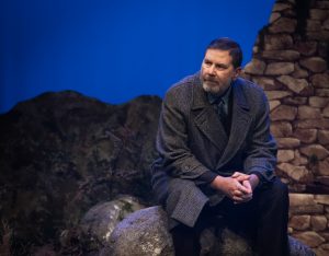 Bill Livingston sits on a rock on a hillside on the outskirts of Lockerbie. It's evening and he is wearing a heavy overcoat to keep out the cold of a Scottish evening. He stares off into the distance, concerned for his wife who continues to roam the hills each day looking for her sons remains.