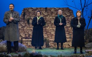 Bill, Olive, Woman Number 1 and Number 2 standing with lit candles as part of the vigil. Each one contemplating the loss which brought them to the hills of Lockerbie.